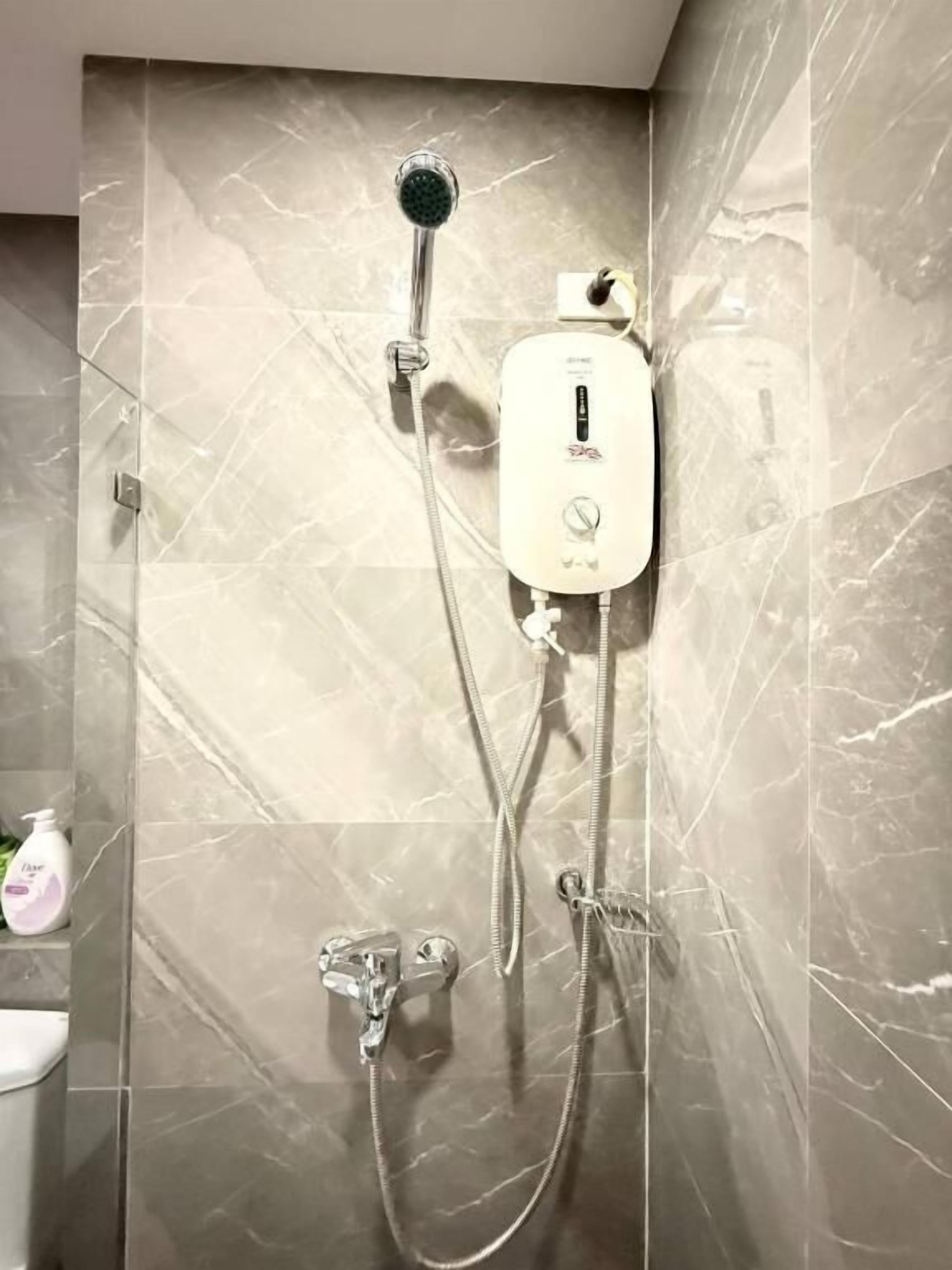 Une douche équipée d’un pommeau de douche à main et d’un panneau de commande fixé au mur.