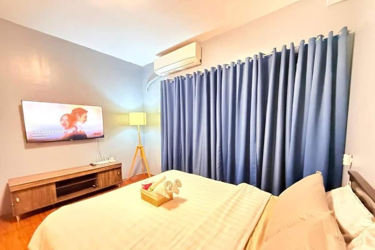 A hotel room with a bed, a TV, a lamp, and curtains.
