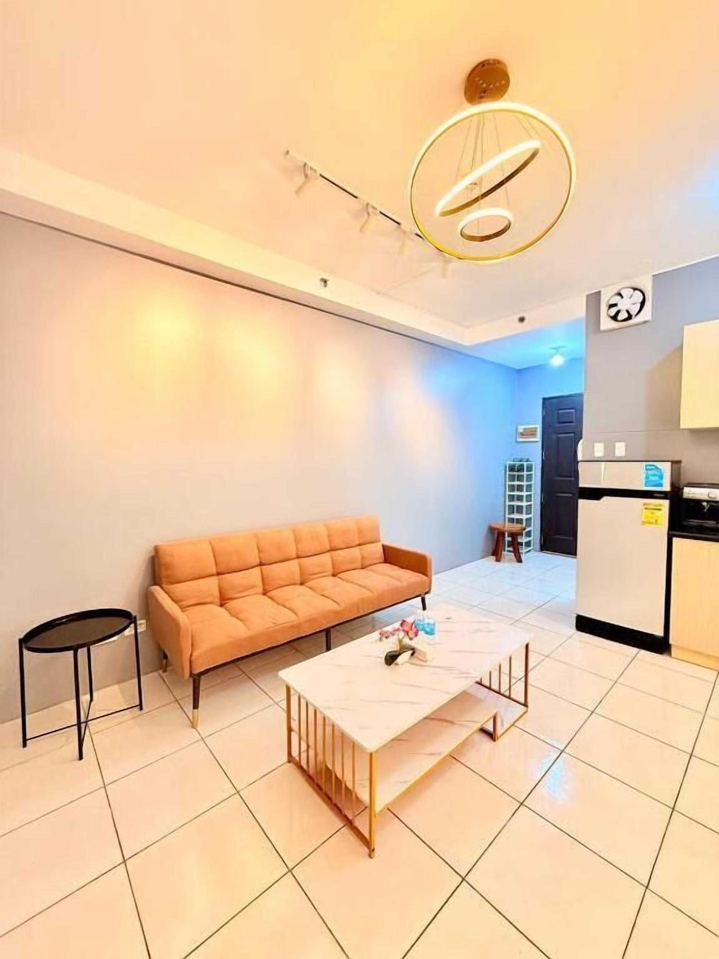 A modern living room with a sofa, a coffee table, and a kitchen area in the background.