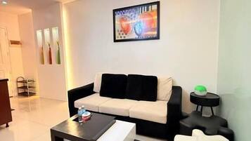 A modern living room with a sofa, a coffee table, and a unique white pouf.