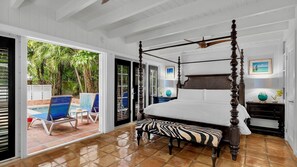 Una cama con dosel y un banco estampado con diseño de cebra, con vistas a una piscina y una puerta que da al exterior.