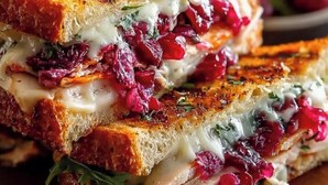 A grilled sandwich with visible layers of meat, cheese, and cranberry sauce. - Sea bridge view hotel mbarara (Mbarara)