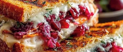 A grilled sandwich with visible layers of meat, cheese, and cranberry sauce.