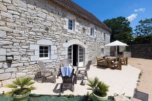 A stone building with a patio area featuring outdoor furniture and a pool. - Le Ventoulou : Gîte familial 9 pers - Dordogne Valley - Pets allowed (Thégra)