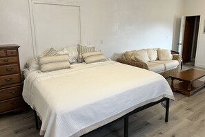 A bedroom with a bed, dresser, sofa, and coffee table.