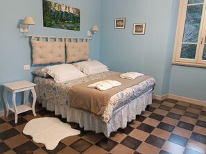 A bedroom with a bed, two nightstands, a white rug, a window, and wall art. - Il Giardino di San Martino (Saliceto)