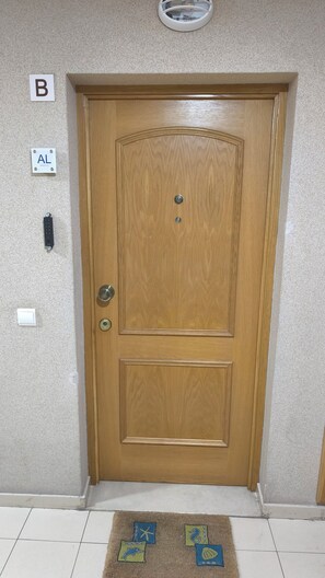 A wooden door with a keyhole and a lock, a wall-mounted light fixture, and a small rug with animal and sea creature designs. - OLD TOWN, Apt. 110m2 on Avenida da Liberdade, AIR CONDITIONING/CAPBLE TV/FREE Wi-Fi (Albufeira)