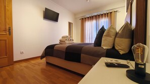 A hotel room with a bed, a flat-screen TV mounted on the wall, a bedside table with a remote control, and a lamp. - OLD TOWN, Apt. 110m2 on Avenida da Liberdade, AIR CONDITIONING/CAPBLE TV/FREE Wi-Fi (Albufeira)