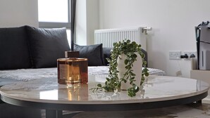 Mesa redonda con una botella y una planta en maceta en una habitación moderna, con cama y radiador.