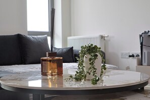 Ein runder Tisch mit einer Flasche und einem Blumentopf in einem modernen Zimmer mit einem Bett und einer Heizung.