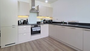 Una cocina moderna con armarios blancos, una campana extractora de acero inoxidable y un horno empotrado.