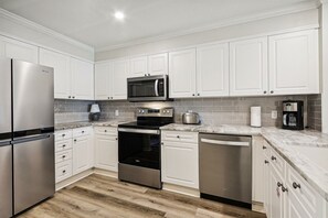 A modern kitchen with stainless steel appliances, white cabinetry, and a tiled backsplash. - ☀️Renovated 3BR End-Unit~Golf Cart~Patio-Community Pool~Villa Bliss☀️ (Miramar Beach)