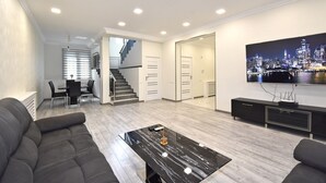 Una sala de estar moderna con un sofá, una mesa de centro, un televisor y una escalera que lleva a otra habitación.