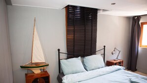 A bedroom with a bed, a nightstand, a wooden cabinet, a sailboat model, and a window with curtains. - Holiday Stay in Center of Verviers (Verviers)