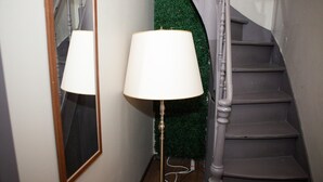 A staircase with a dark handrail and steps, a green wall with a textured surface, and a floor lamp with a white shade. - Holiday Stay in Center of Verviers (Verviers)