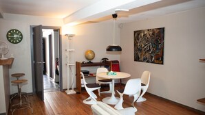 A room with a wooden floor, a round table with white chairs, a globe, a painting, and a clock on the wall. - Holiday Stay in Center of Verviers (Verviers)