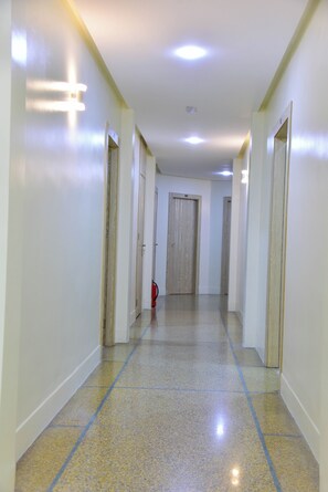 A long, narrow hallway with white walls and a tiled floor, leading to a door at the end. - Hôtel Atlas (Tangier)
