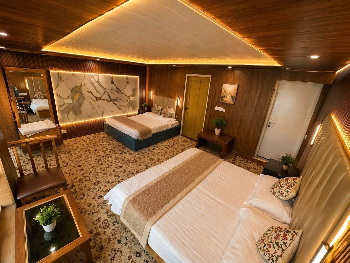Una habitación de hotel moderna con una cama grande, una zona de estar con una silla y una mesa, un espejo y un techo de madera.