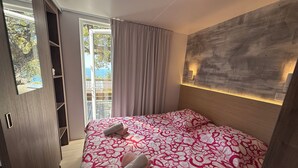 A bedroom with a bed, a window, a door, and a wall-mounted light fixture. - Luxury bungalow - Sea view - Heated pool 4 (Saint-Raphaël)