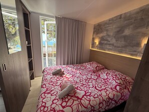 A bedroom with a bed, a window, a door, and a wall-mounted light fixture. - Luxury bungalow - Sea view - Heated pool 4 (Saint-Raphaël)