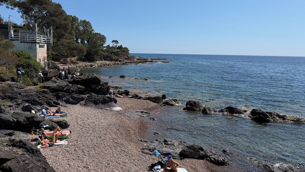 A rocky beach with clear water, a few people sunbathing, and a building with a balcony overlooking the sea. - Luxury bungalow - Sea view - Heated pool 4 (Saint-Raphaël)