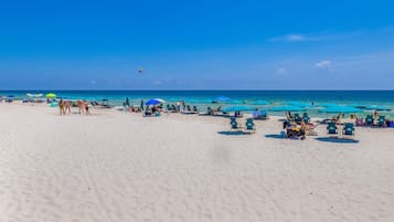 A beach with numerous umbrellas and lounge chairs, indicating a resort setting.
