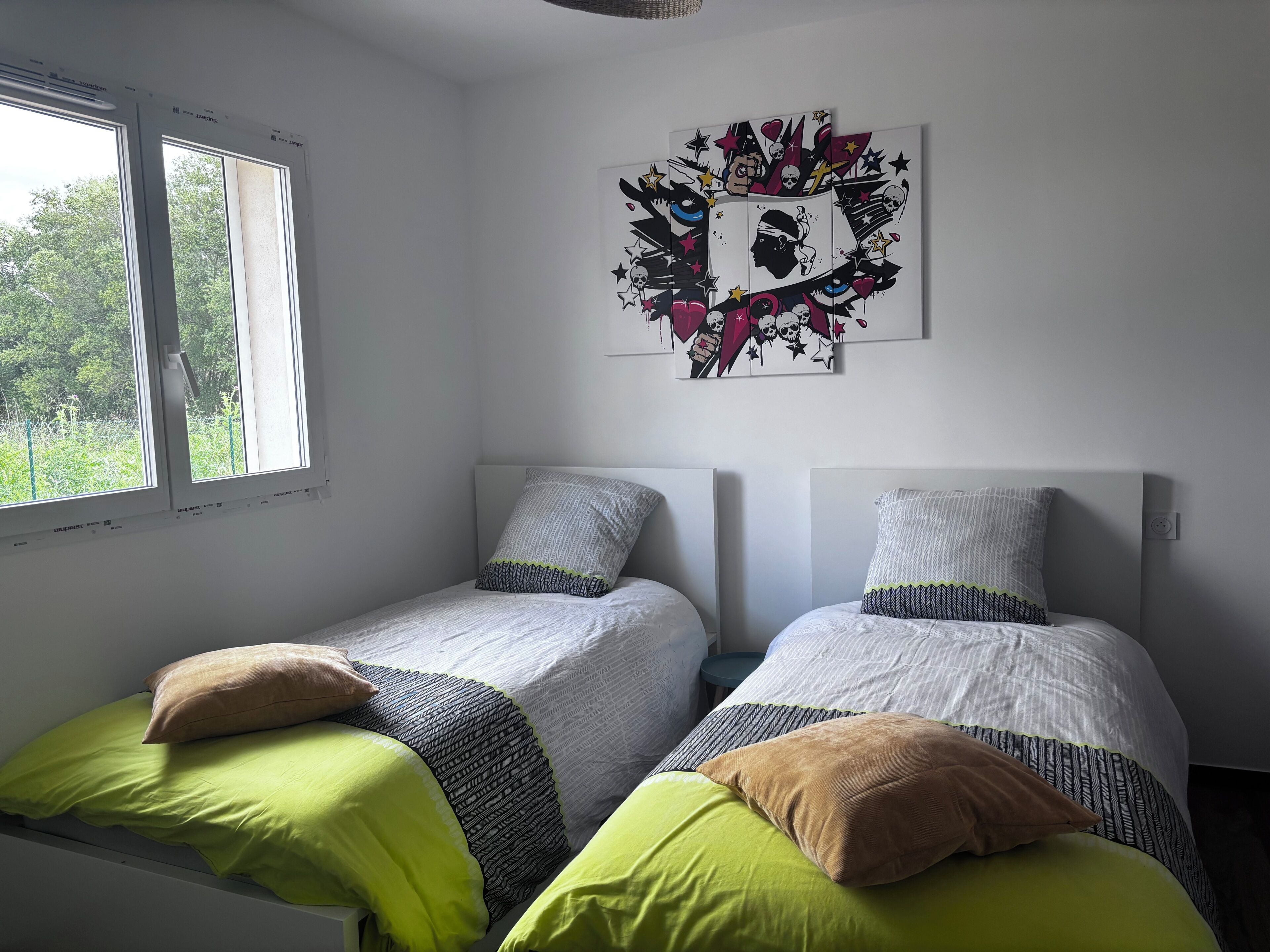 Une chambre avec deux lits simples, une fenêtre et une œuvre d’art accrochée au mur.