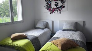 Una habitación con dos camas individuales, un ventanal y una obra de arte en la pared.