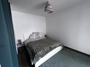 Une chambre à coucher comprenant un lit, une table de chevet, une lampe et un luminaire suspendu.