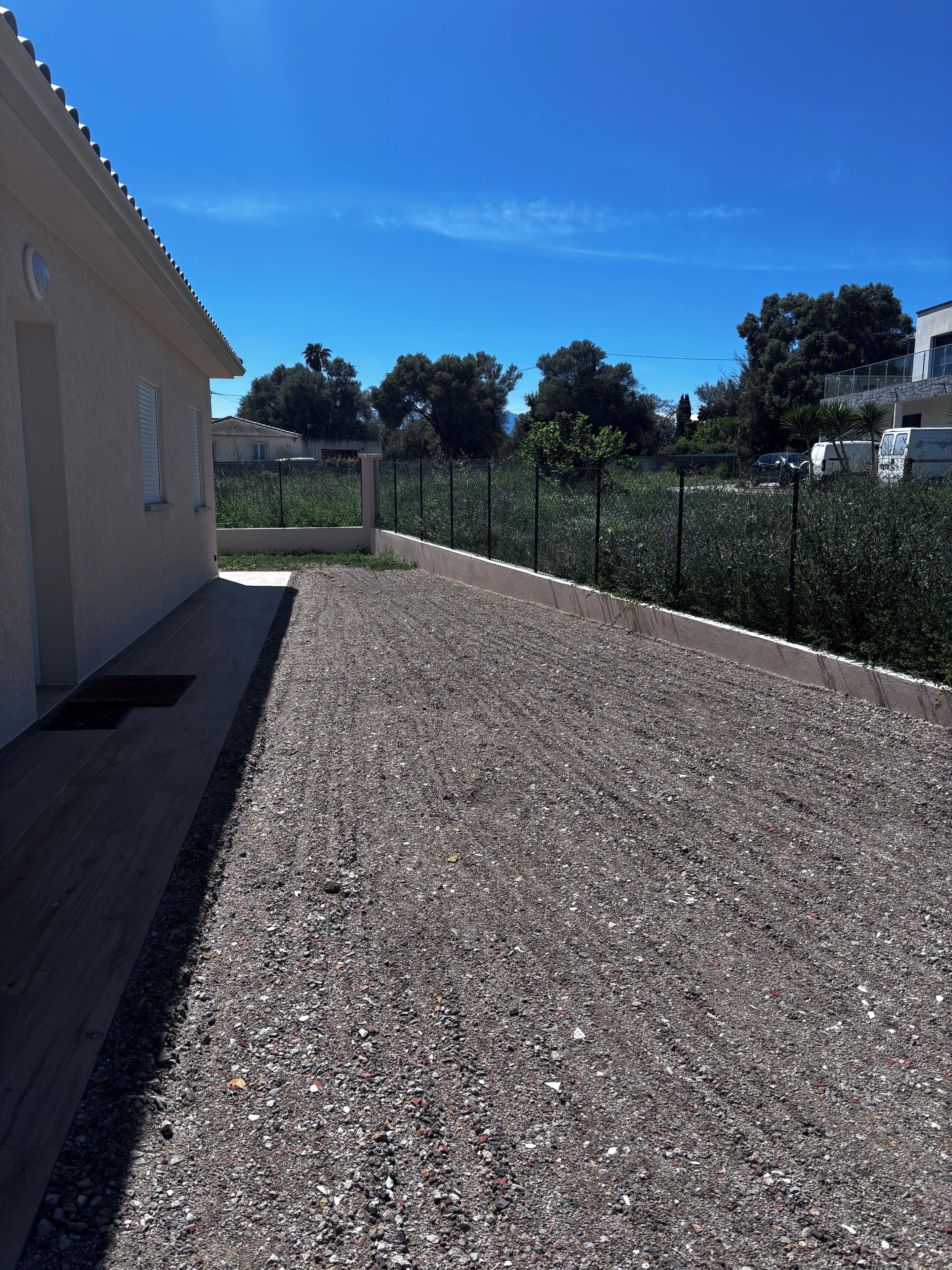 A building with a gravel driveway and a fence.