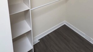 Un vestidor con estanterías blancas y piso de madera.