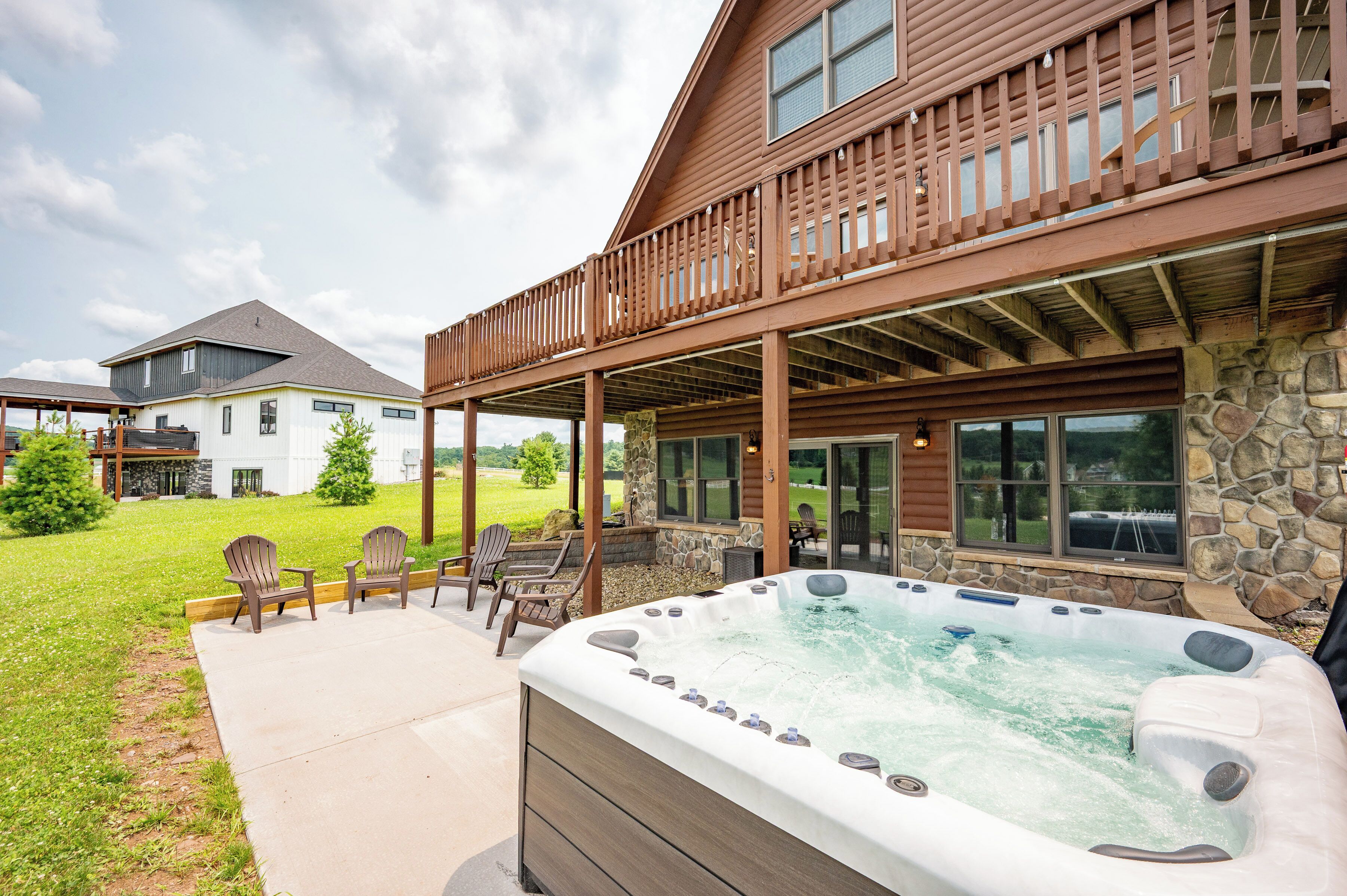 A hot tub with chairs, a covered patio, and a stone wall.