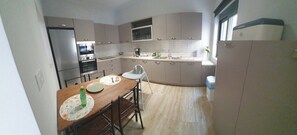 A compact kitchen with a dining area, a refrigerator, oven, and a sink. - Modern cozy home in Kos town (Kos)