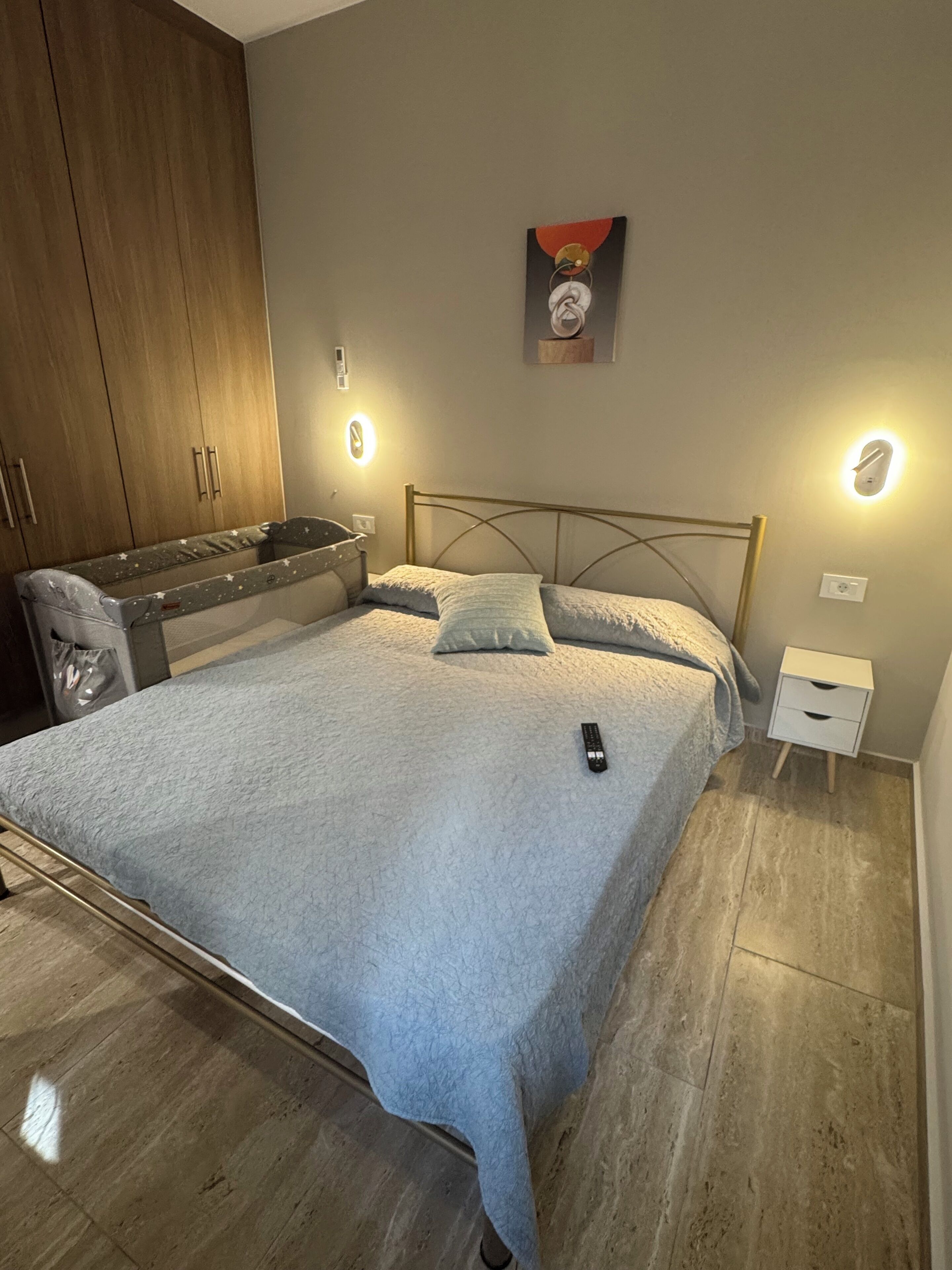 A bedroom with a bed, bedside tables, a wardrobe, and wall-mounted lights.