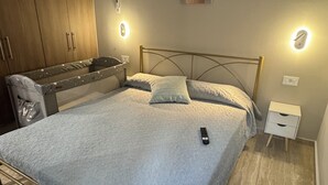 A bedroom with a bed, bedside tables, a wardrobe, and wall-mounted lights. - Modern cozy home in Kos town (Kos)