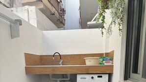 A compact balcony with a washing machine, a sink, and a small table with chairs. - Modern cozy home in Kos town (Kos)
