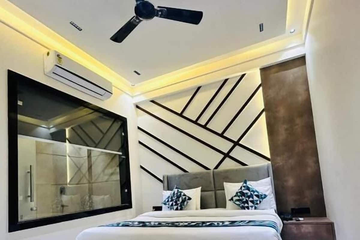 A modern bedroom with a bed, a ceiling fan, a large window, and a geometric wall design.