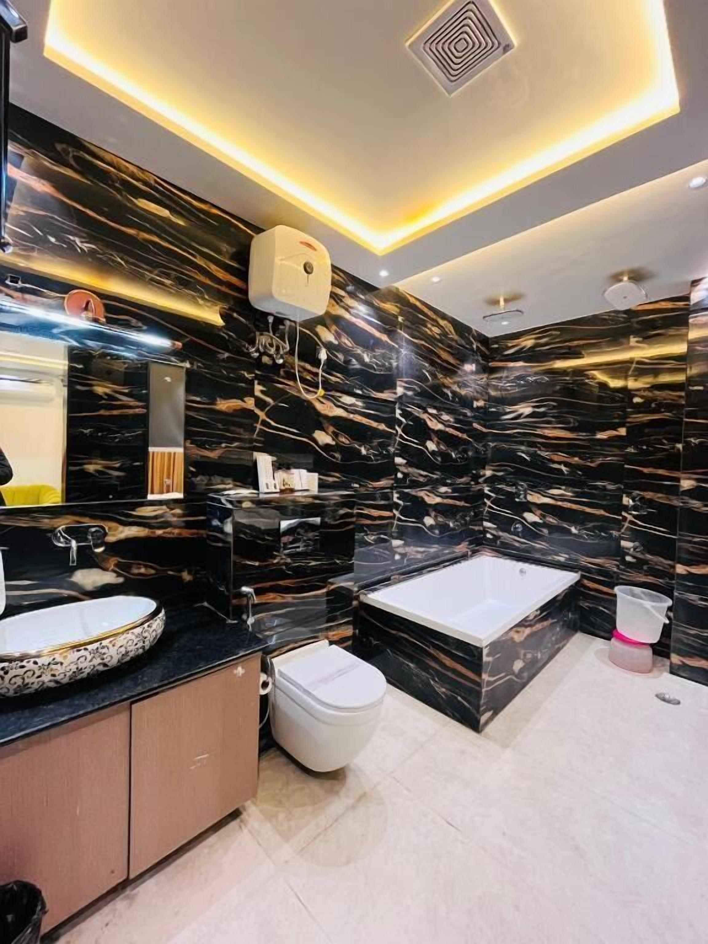 Ein modernes Badezimmer mit einem Marmor-Waschtisch, einer Badewanne und einer Toilette.