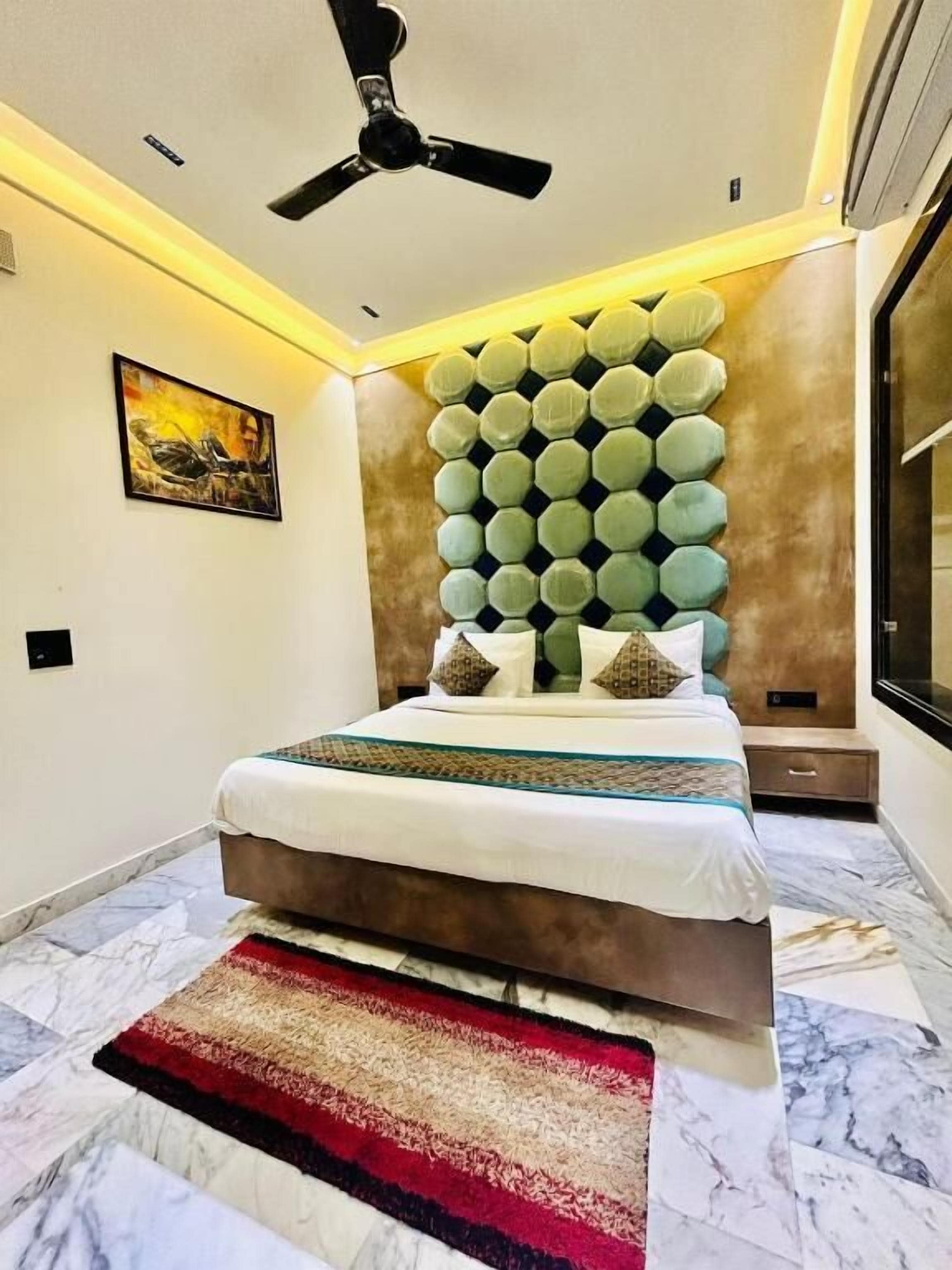 A modern bedroom with a bed, a ceiling fan, a wall-mounted light, and a large window.