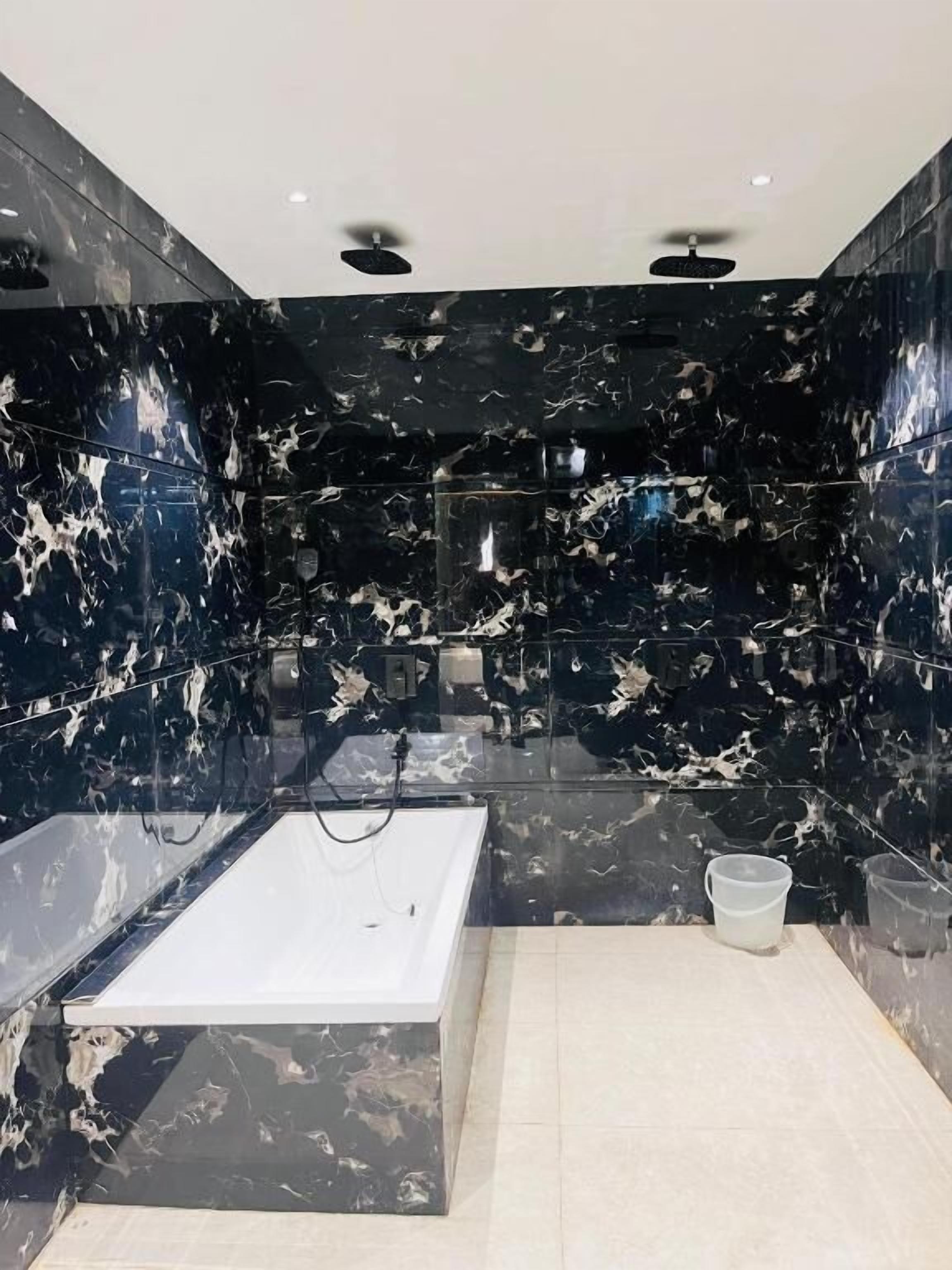 Une salle de bain moderne avec une baignoire, un espace douche et des murs en marbre.