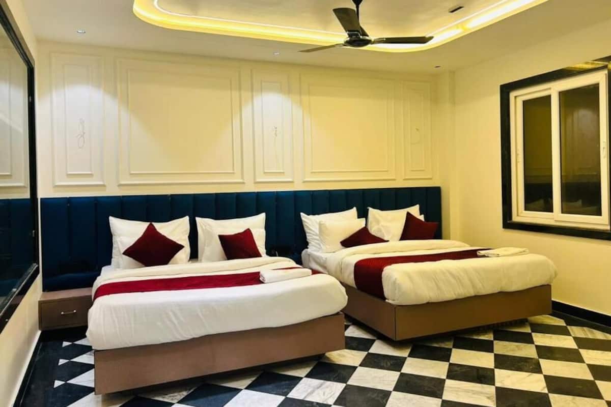 A hotel room with two beds, a checkered floor, a ceiling fan, and a window.