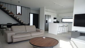 Un salon moderne comprenant un canapé, une table basse, un escalier et un coin cuisine.