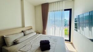 Una habitación de hotel con una cama, una ventana con cortinas, vistas a edificios y un televisor de pantalla plana.