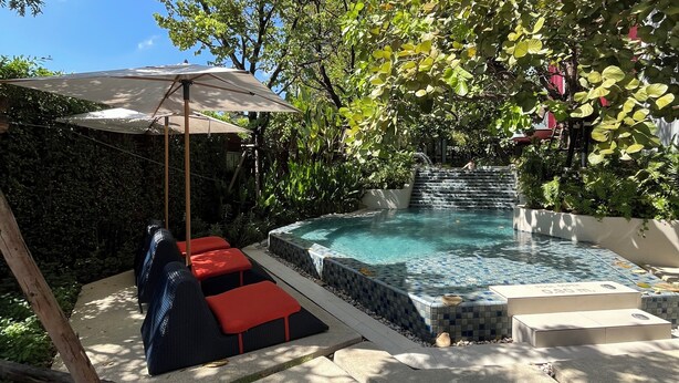 Un área de piscina con un jacuzzi, sillas de descanso y una pérgola.