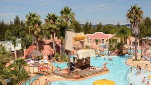A large outdoor swimming pool with multiple water features, palm trees, and a rocky landscape. - Holiday Park Stay With Sun, Slides & Sea (Hyères)