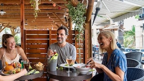 A wooden outdoor dining area with tables, chairs, and hanging plants. - Holiday Park Stay With Sun, Slides & Sea (Hyères)