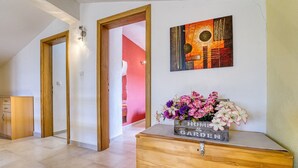 Een hal met een houten kast, een aan de muur hangend schilderij en een bloemstuk.