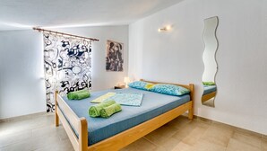 Een slaapkamer met een bed, een gordijn met zwart-wit patroon, een wandspiegel en een schilderij.