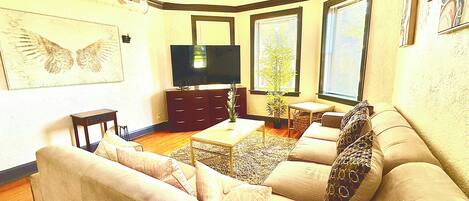 A living room with a sofa, a coffee table, a television, and a ceiling fan.