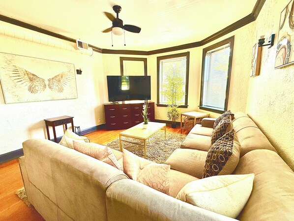 A living room with a sofa, a coffee table, a television, and a ceiling fan. - Upscale 1BR -Near Midway Airport - Free Parking & Fast CTA Access (Chicago)